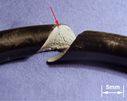Figure 1 - SAE 9254 Helical Spring failed prematurely in service due to poor quality peened surface. Arrow indicates start of failure region. No fatigue crack-growth visible. Magnification 5x. Courtesy: Testmat.