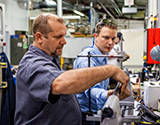 Production Manager Andy Kerber helps Stan Bovid, Director of Materials Research, pinpoint exact measurement for laser peen forming for a new customer solution. Laser peen forming uses the precision and power of laser plasma explosions to adjust the straightness and curvature of metal parts, from small castings to hull sections for high-performance naval vessels. 