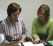 Alice Loy (left) and Kelli Wolfe confer on a report