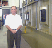 Clemco President, Arnie Sallaberry, adjacent to an engineered automated system for cleaning pipes